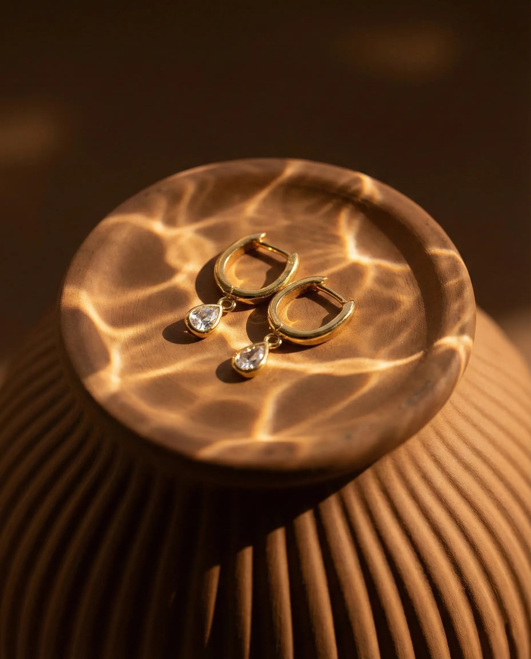 timeless-teardrop-sparkle-earrings-modern-aesthetic, 18k-gold-plated-huggies-detail, gift-ideas-for-women-delicate-jewelry, high-clarity-zirconia-drop-earrings-europe, luxury-boutique-jewelry-netherlands, artistic-jewelry-flatlay-photography