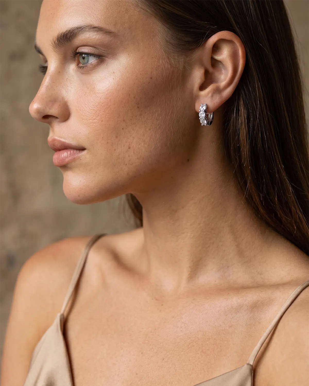 blanca-crystal-huggie-hoop-earrings-artistically-displayed-in-a-mother-of-pearl-shell-minimalist-jewelry-photography-for-gifting-inspiration