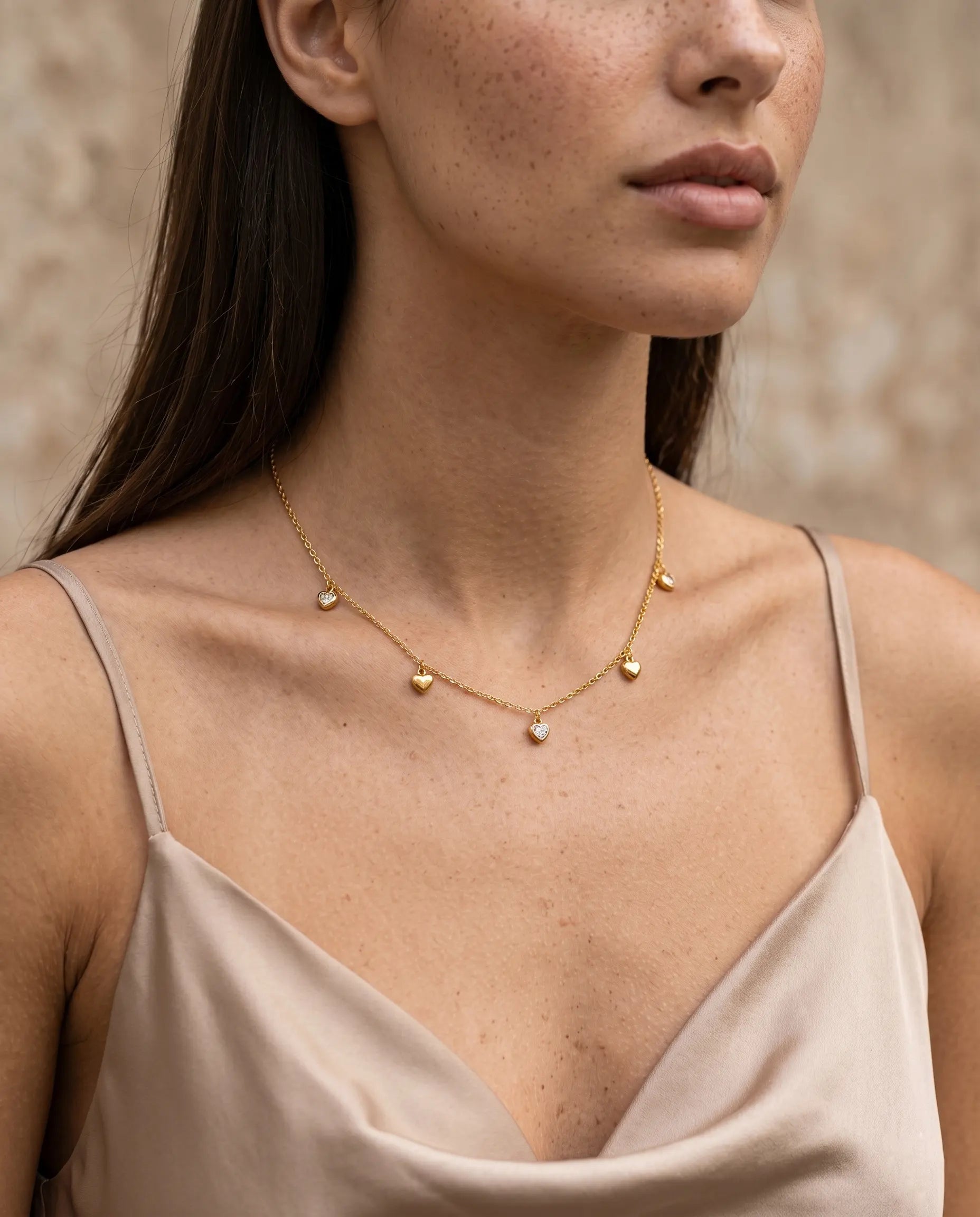 isabella-heart-necklace-artistic-shot-in-natural-warm-light-showcasing-the-delicate-chain-and-stationed-charms
