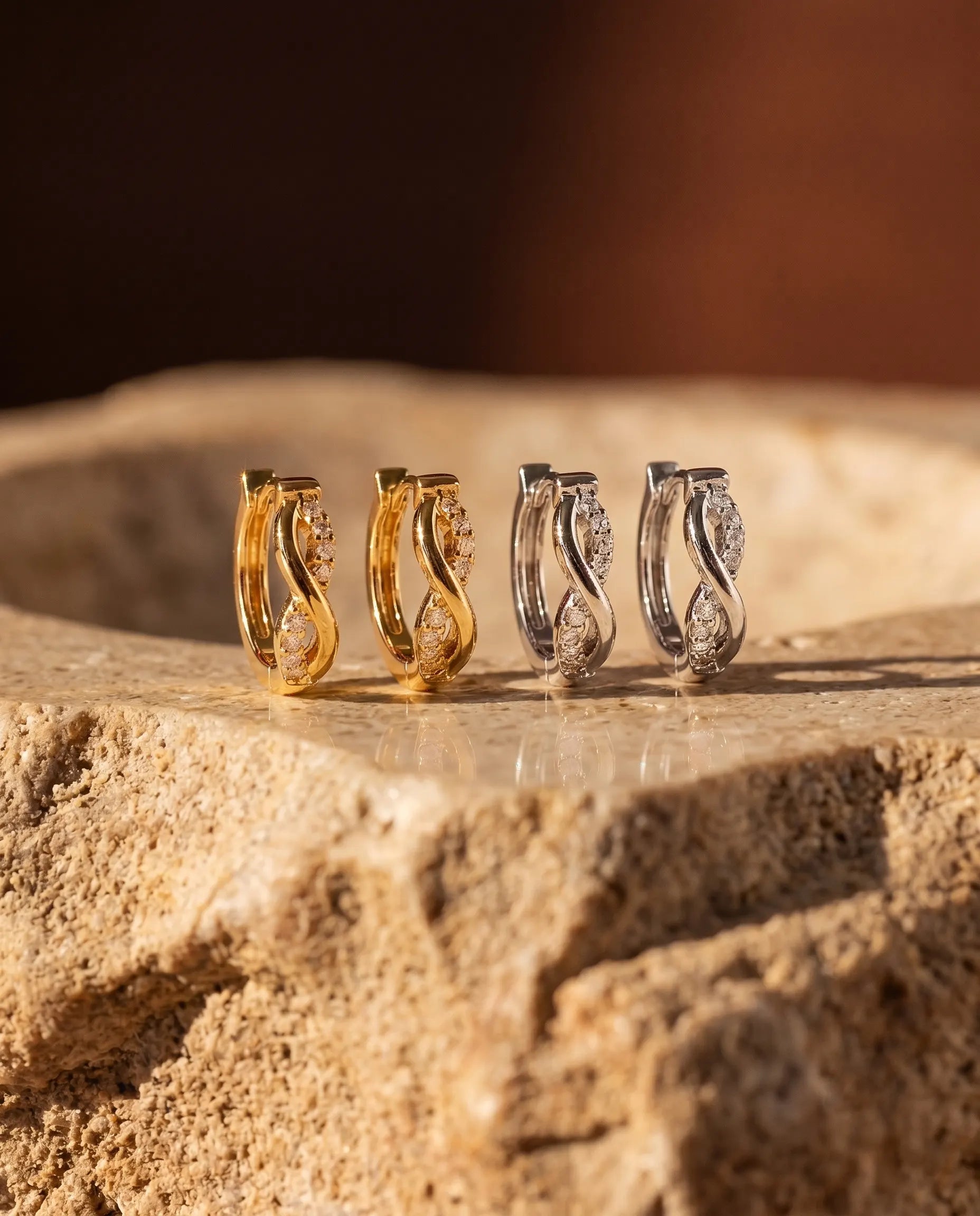 luiza-silver-zirconia-huggie-earrings-displayed-on-textured-surface-modern-minimalist-jewelry-photography