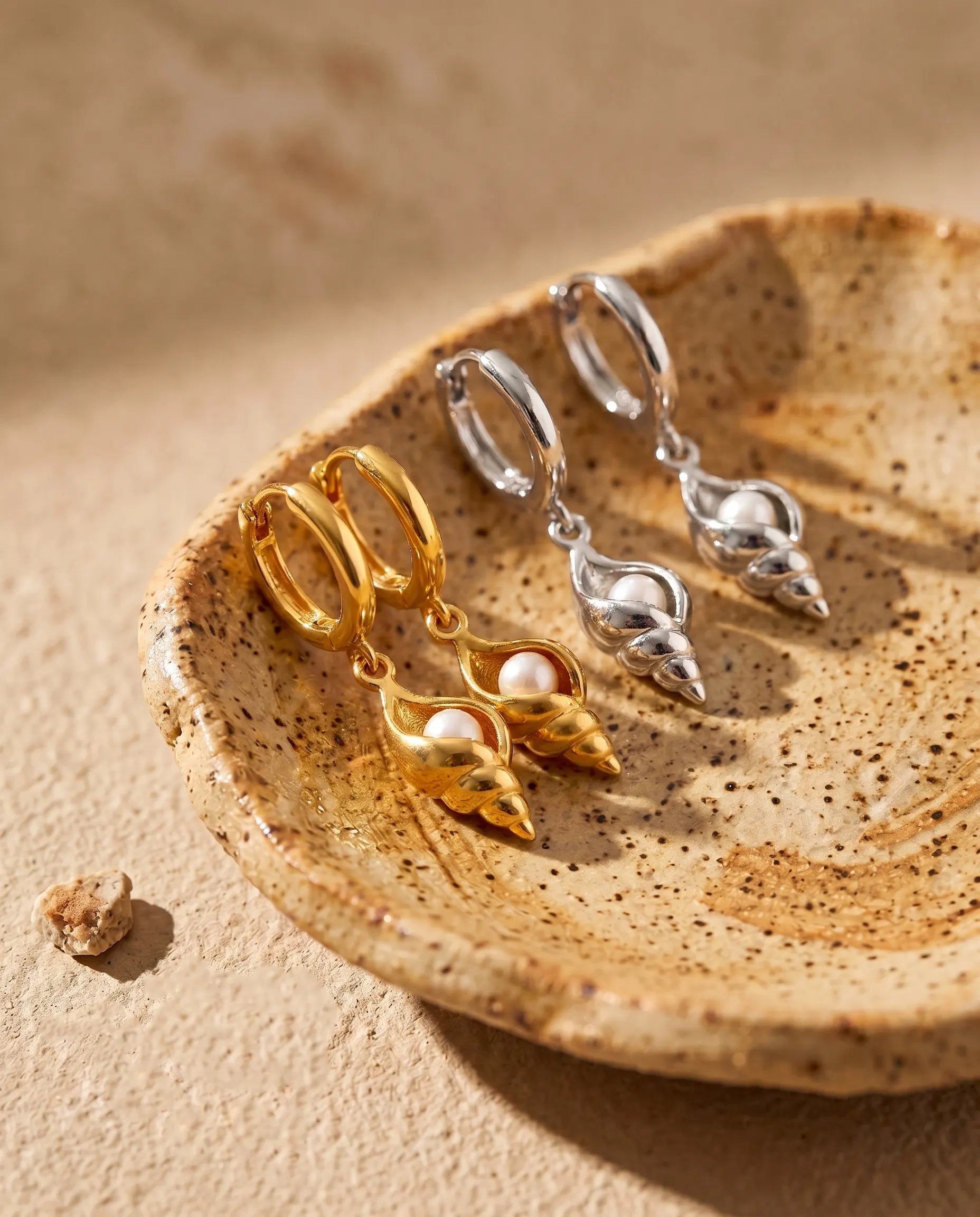 marea-pearl-shell-drop-earrings-resting-on-minimalist-sand-like-surface-photography-for-luxury-jewelry-enthusiasts