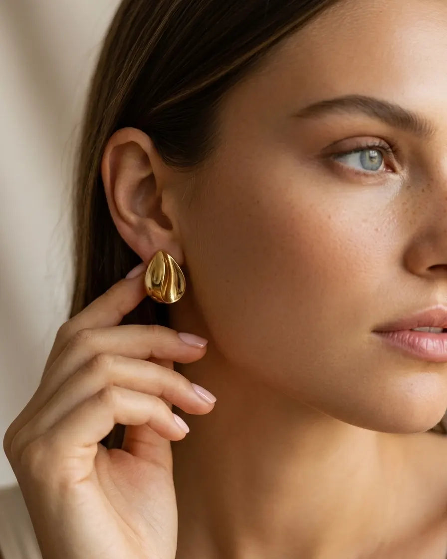 model-wearing-gold-rhea-teardrop-studs-lifestyle, elegant-modern-bold-jewelry-on-ear, professional-women-luxury-accessories, chic-gold-organic-earring-styling, luxury-lifestyle-brand-model