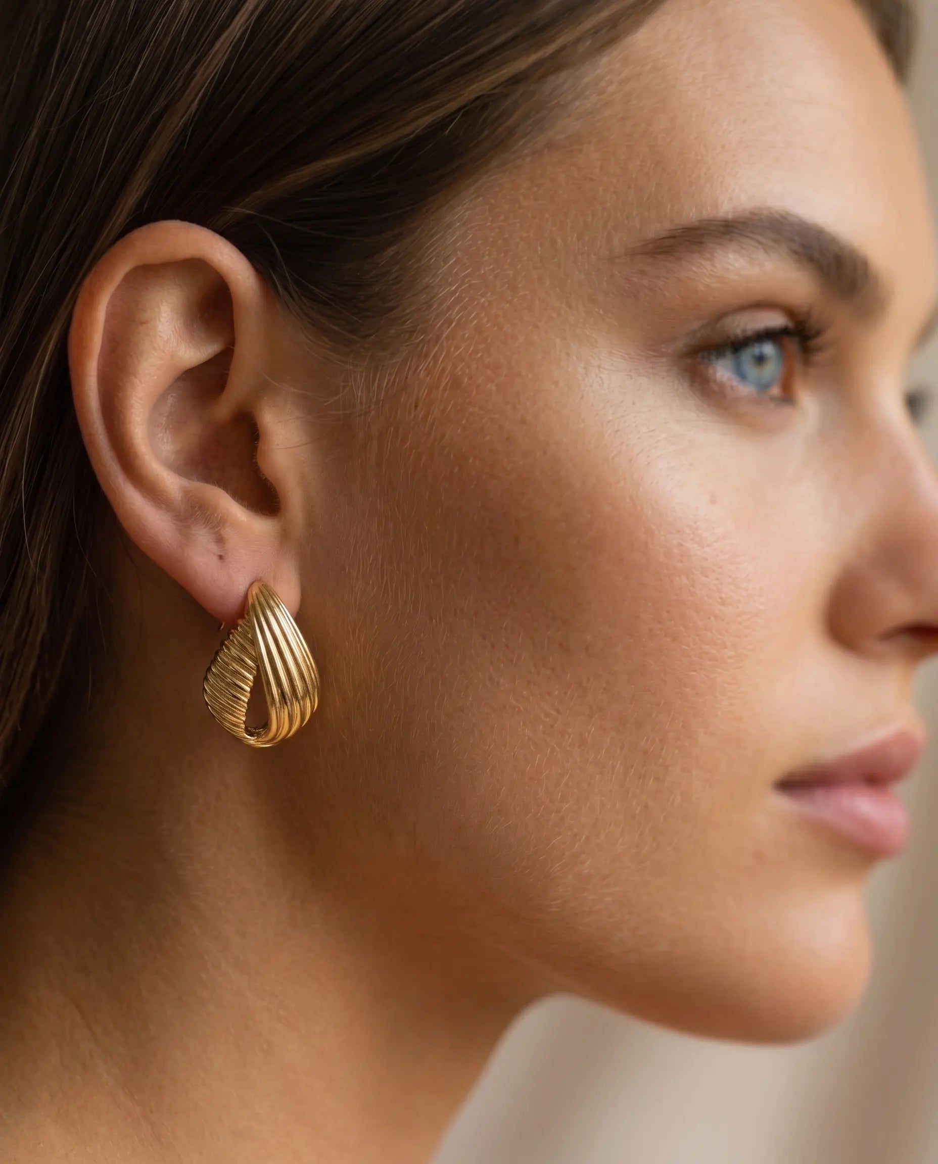 model-wearing-gold-rivera-chunky-hoops-lifestyle, elegant-modern-bold-jewelry-on-ear, professional-women-luxury-accessories, chic-gold-ribbed-hoop-styling, luxury-lifestyle-brand-model