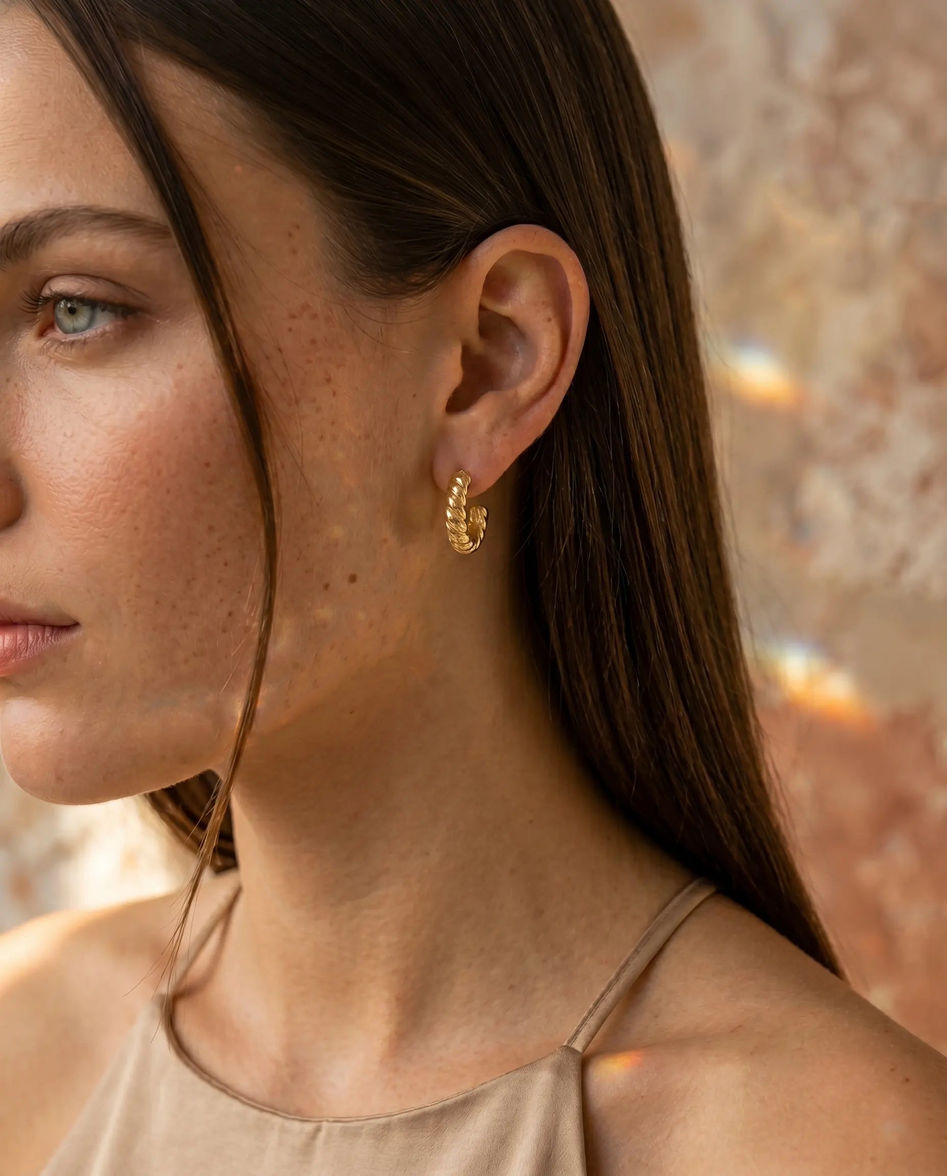model-wearing-silver-museful-twisted-earrings-lifestyle, elegant-modern-sparkle-jewelry-on-ear, professional-women-luxury-accessories, chic-silver-spiral-hoop-styling, luxury-lifestyle-brand-model