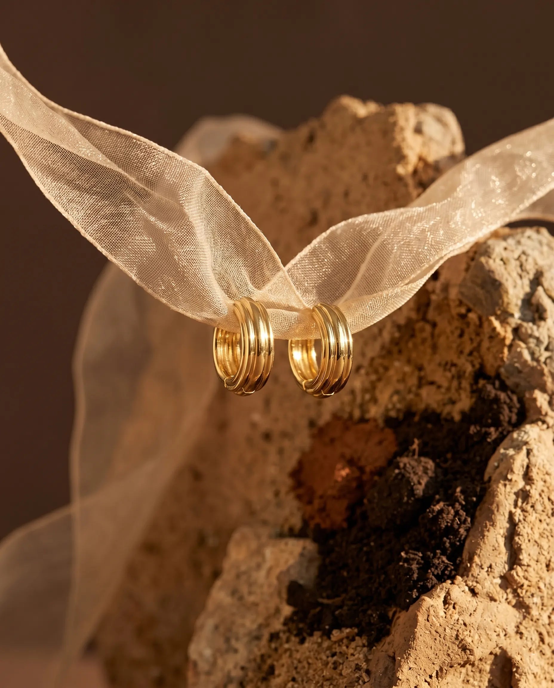 olive-textured-huggie-hoops-displayed-with-delicate-ribbon-minimalist-jewelry-photography-for-senya