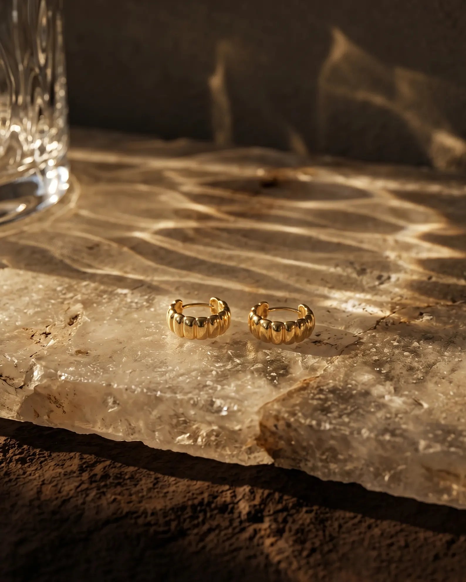 olvera-ribbed-huggie-hoops-resting-on-minimalist-ceramic-dish-photography-for-luxury-jewelry-enthusiasts