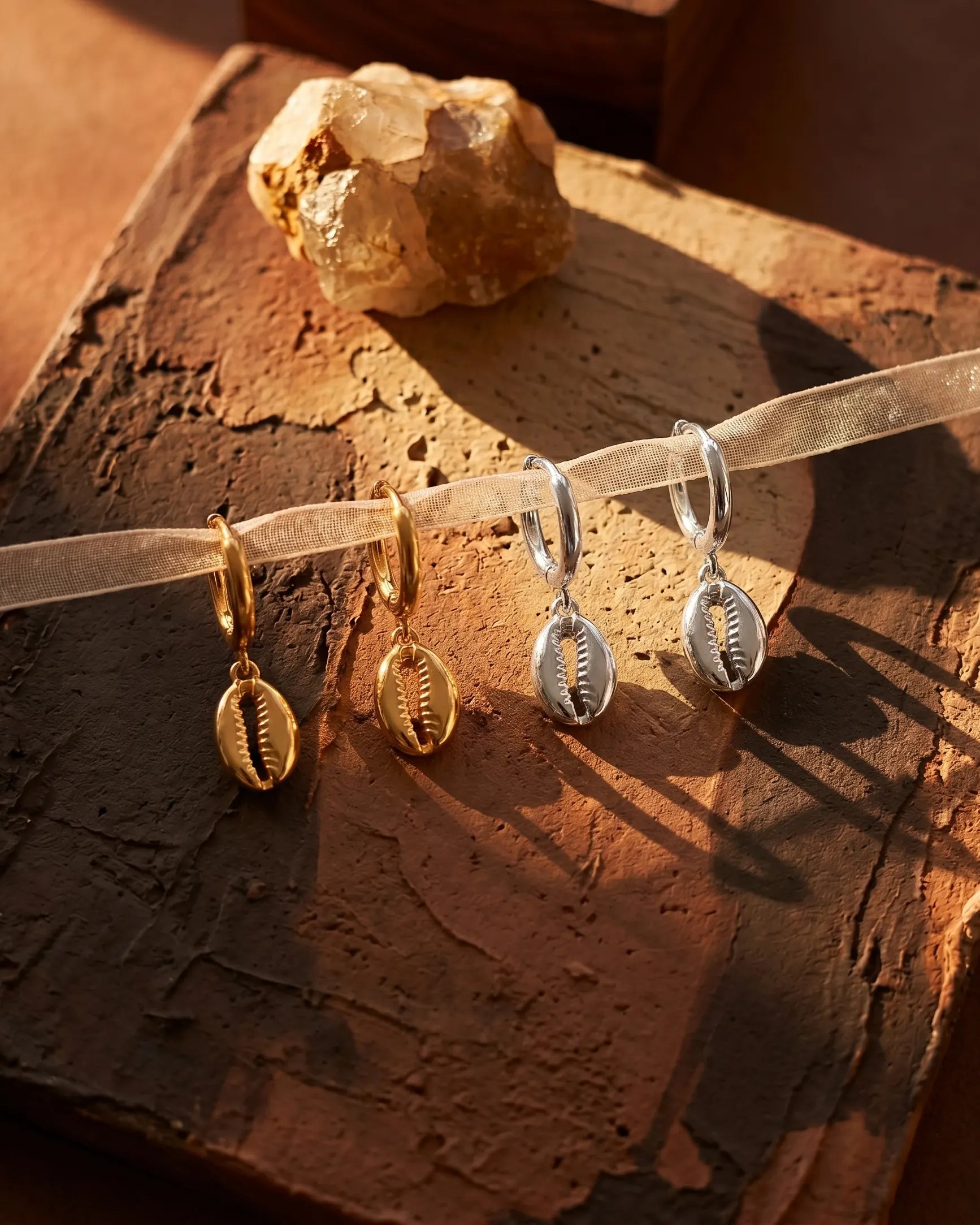sand-cowrie-shell-huggie-hoops-captured-in-warm-natural-light-to-emphasize-the-coastal-minimalist-aesthetic