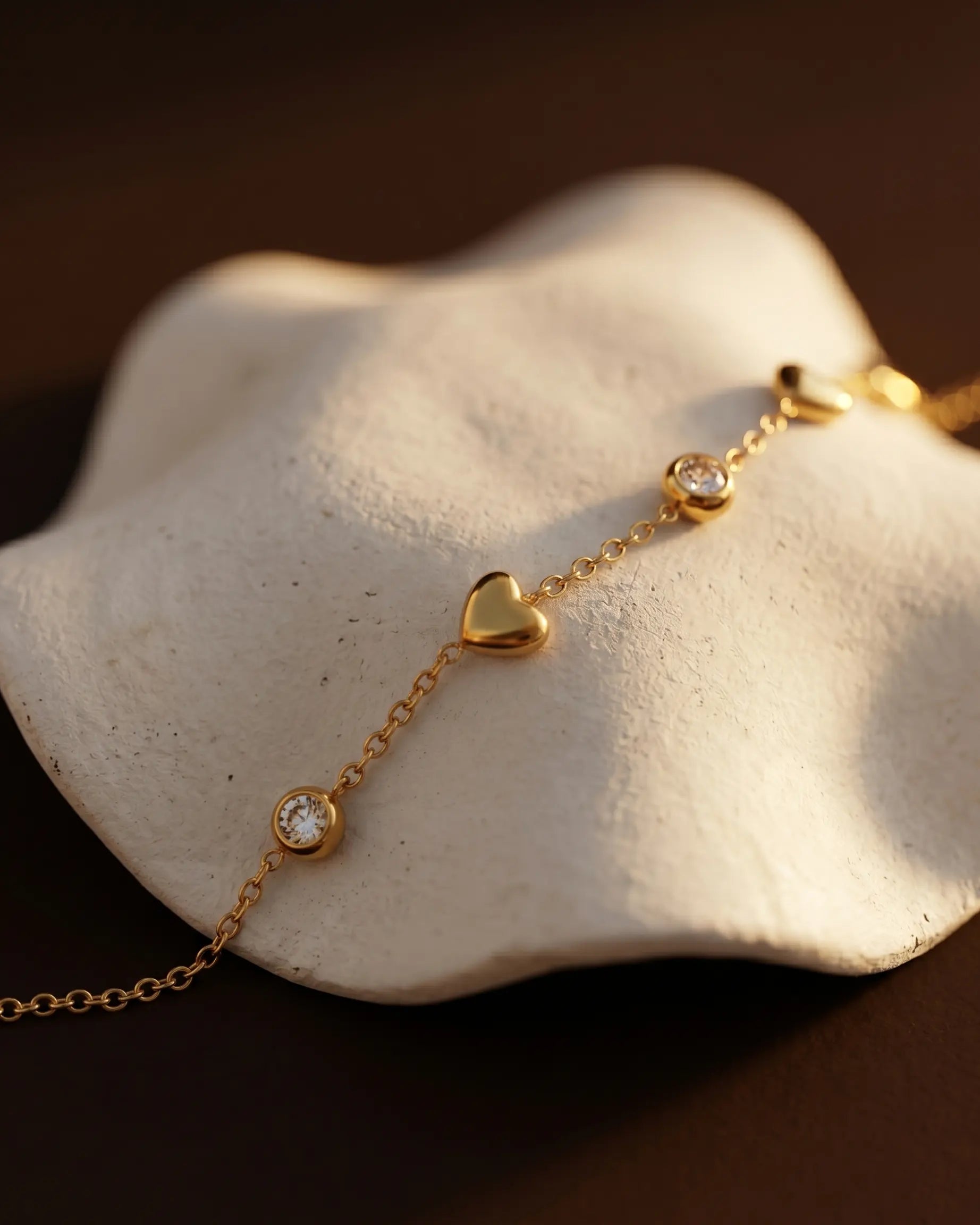 hartel-heart-bracelet-artistic-shot-in-natural-warm-light-showcasing-the-delicate-chain-and-heart-charms