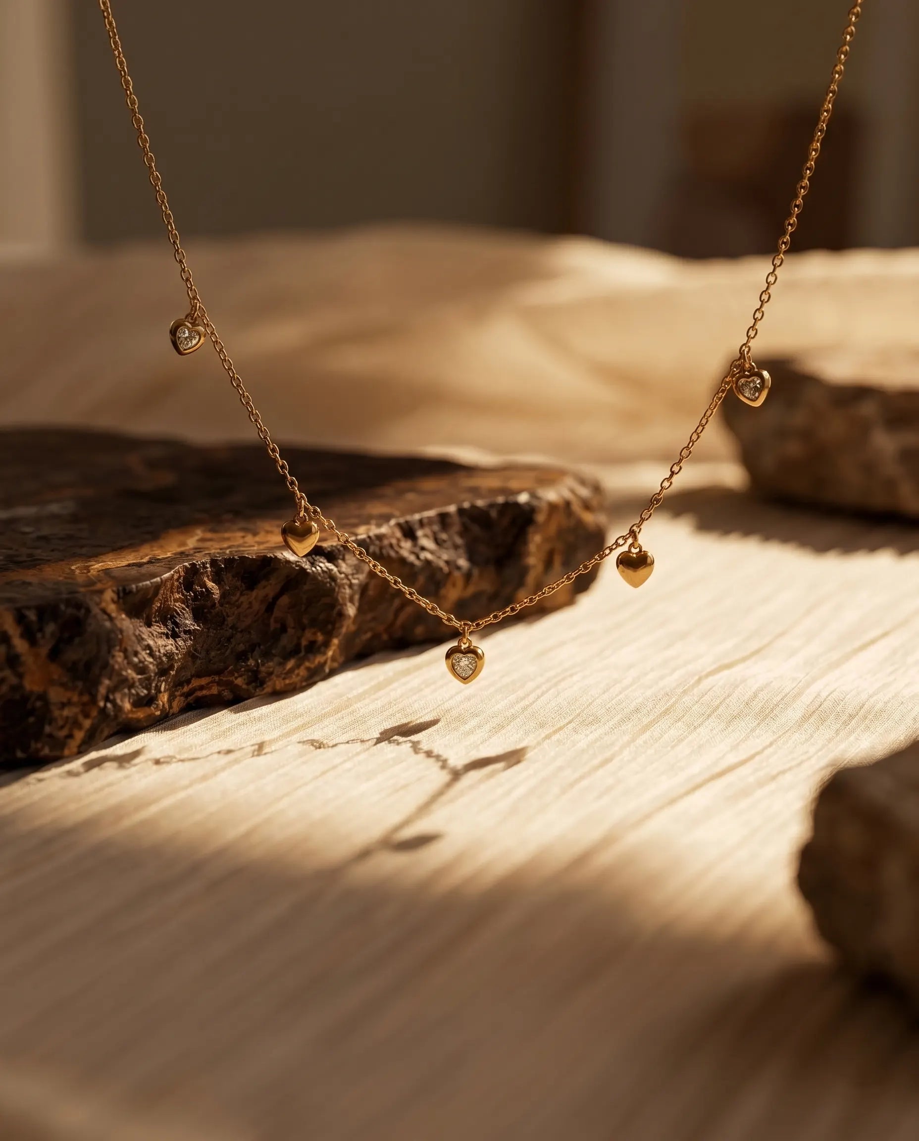 close-up-of-isabella-heart-necklace-displayed-on-textured-ceramic-background-highlighting-gold-finish