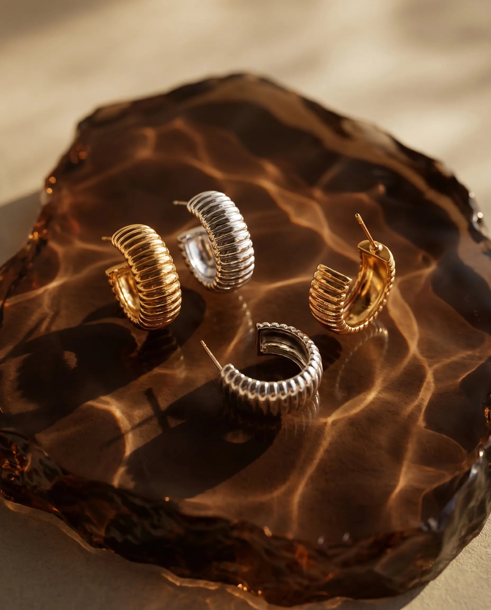 glam-ribbed-huggie-hoops-resting-on-minimalist-display-photography-for-luxury-jewelry-enthusiasts