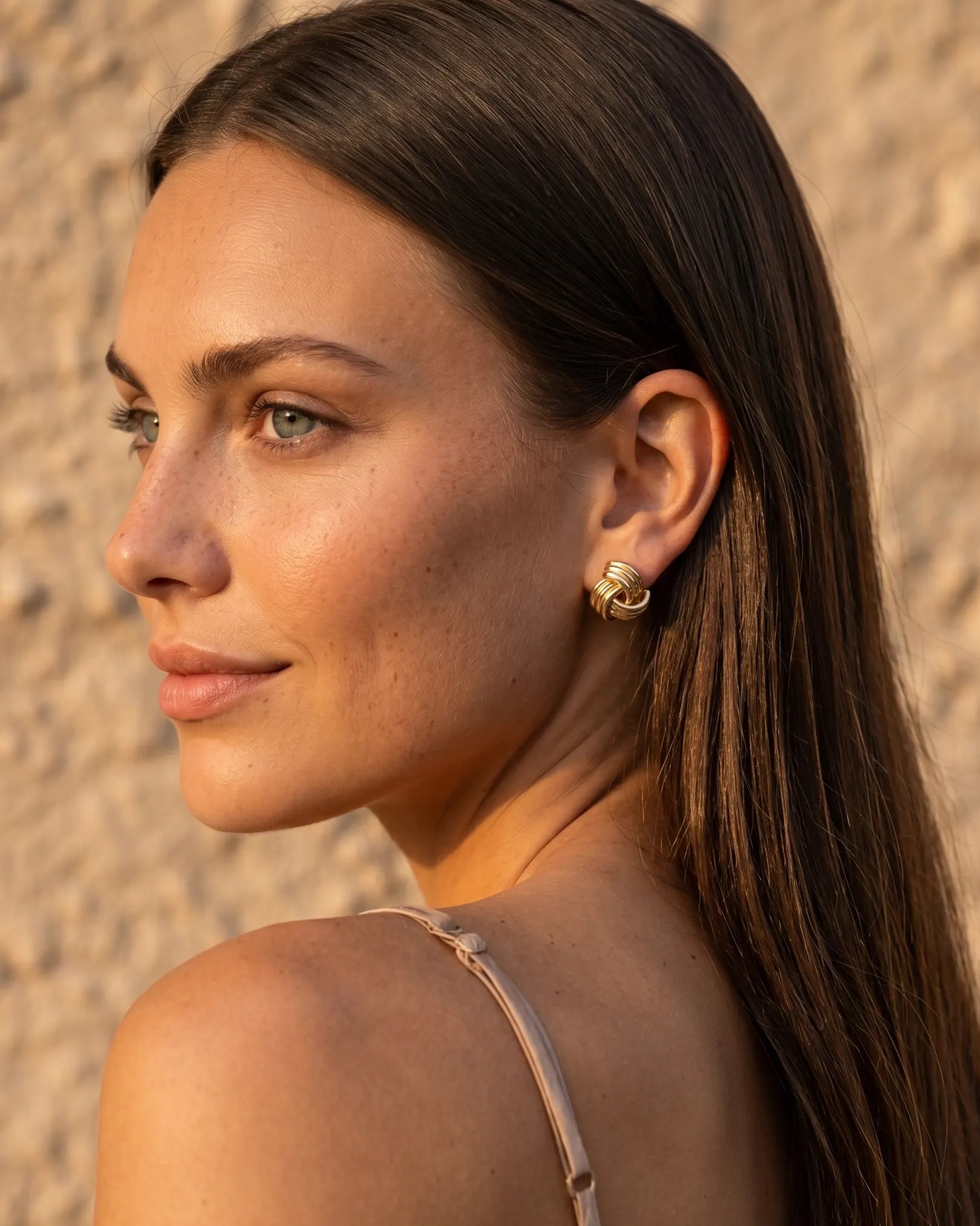 model-wearing-gold-samira-knot-earrings-lifestyle, elegant-modern-classic-jewelry-on-ear, professional-women-luxury-accessories, chic-gold-knot-stud-styling, luxury-lifestyle-brand-model