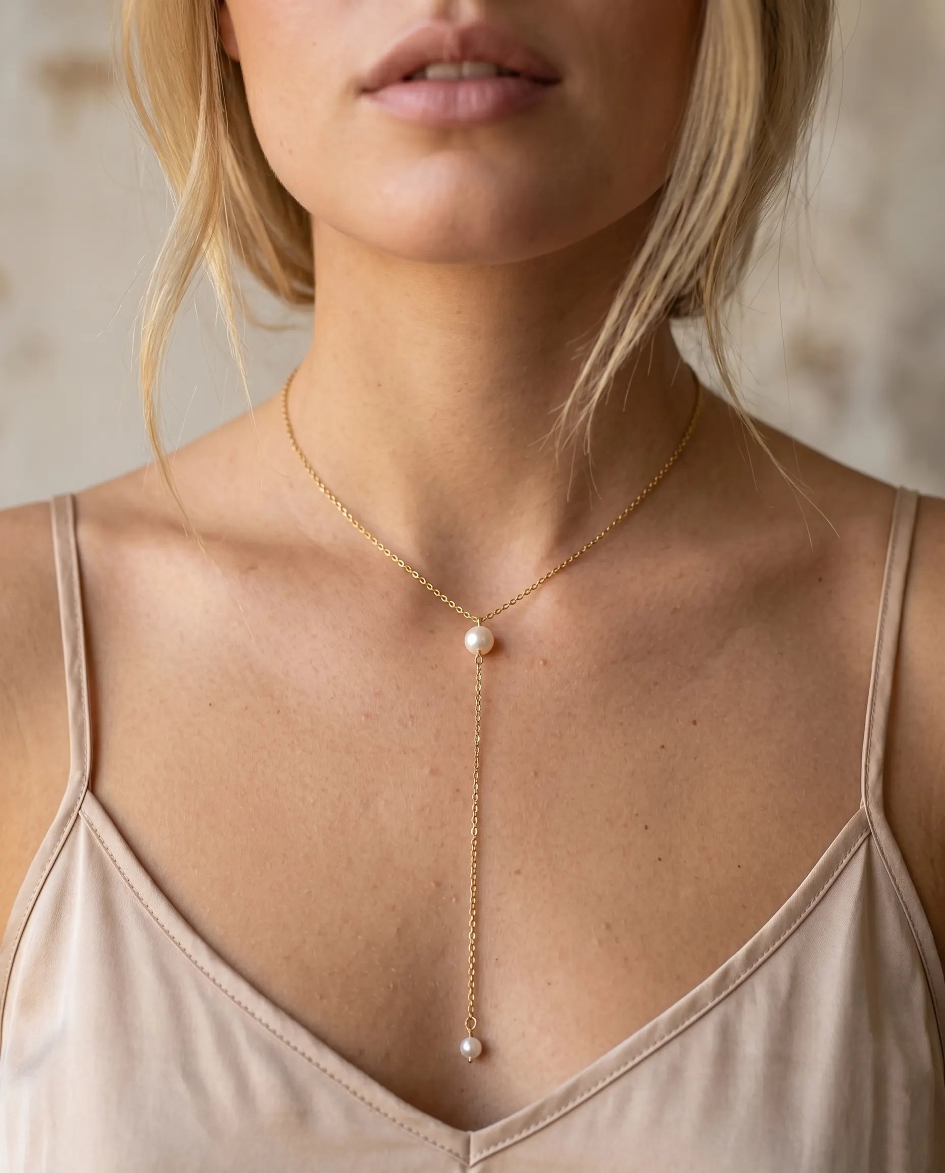 model-wearing-gold-pacifica-pearl-lariat, elegant-statement-jewelry-lifestyle, professional-women-jewelry-style, chic-minimalist-accessories-for-evening-wear, luxury-lifestyle-brand-photography, premium-pearl-necklace-model-shot