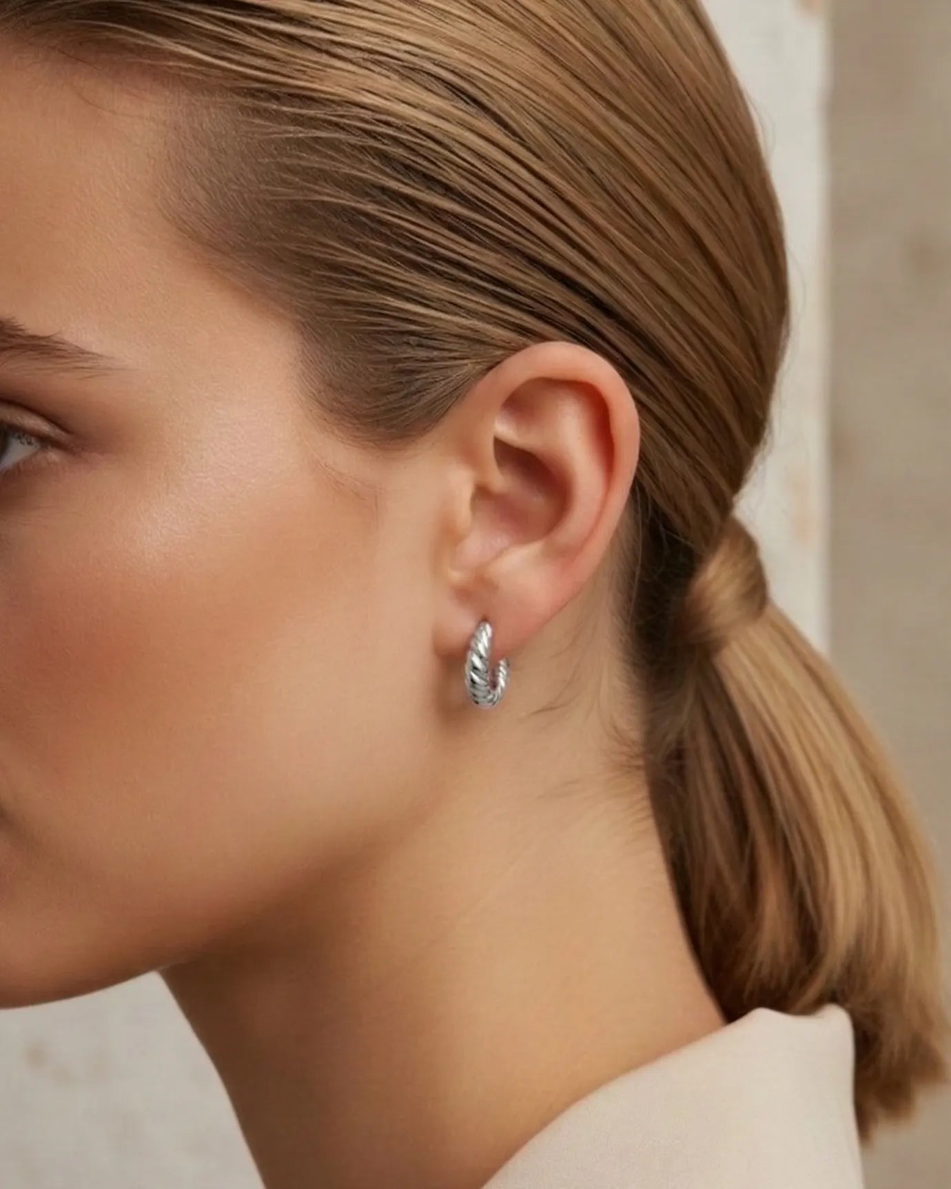 model-wearing-silver-museful-twisted-earrings-lifestyle, elegant-modern-sparkle-jewelry-on-ear, professional-women-luxury-accessories, chic-silver-spiral-hoop-styling, luxury-lifestyle-brand-model