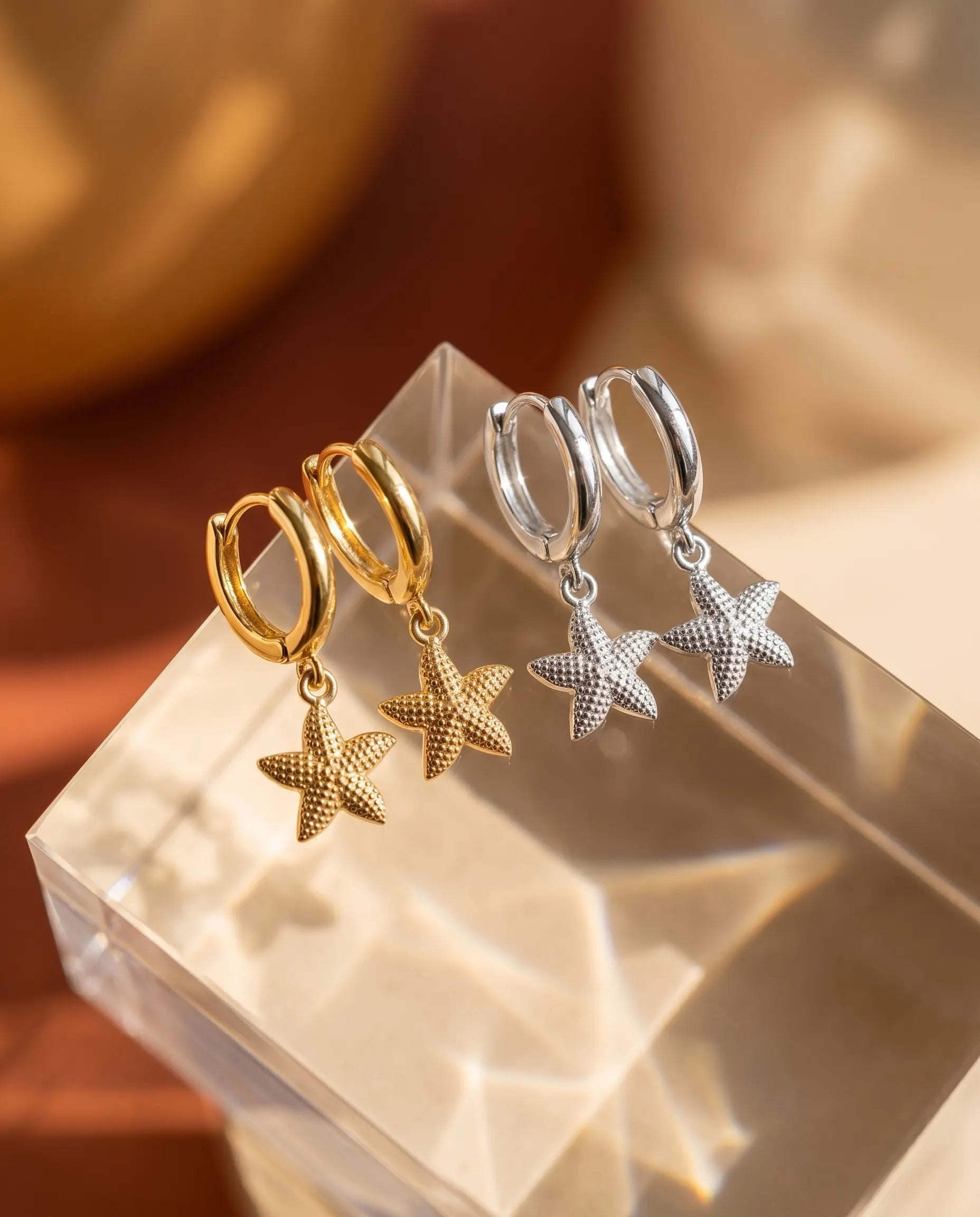 nerella-starfish-huggie-hoops-in-gold-and-silver-captured-in-warm-light-minimalist-coastal-jewelry-photography