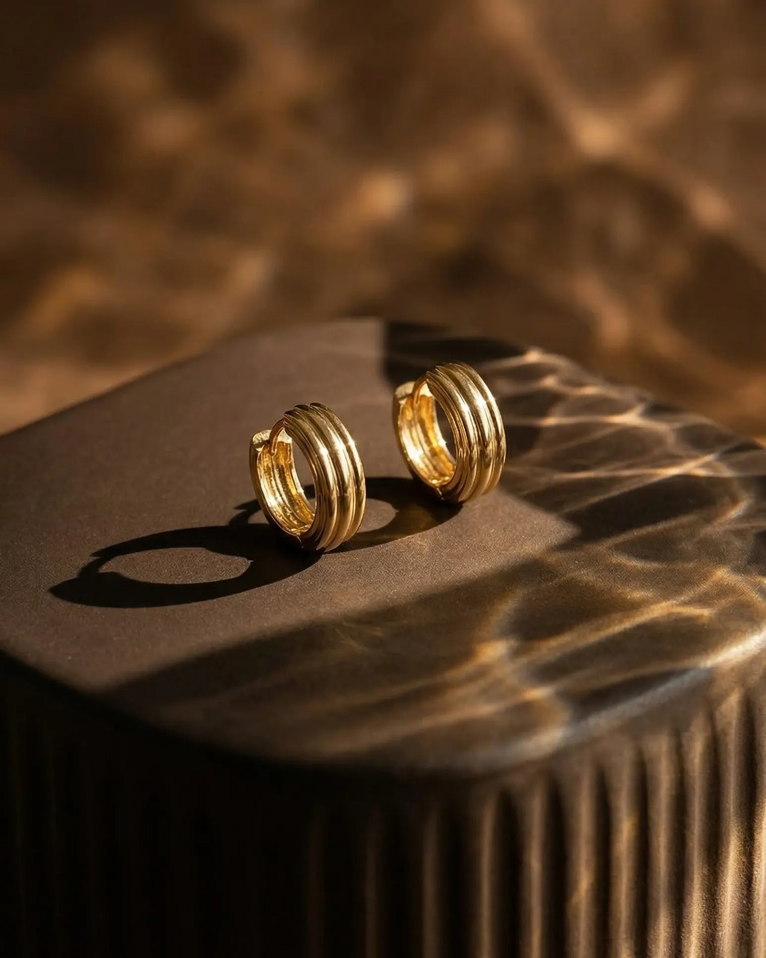 olive-textured-huggie-hoops-in-warm-natural-light-highlighting-the-sculptural-ribbed-design