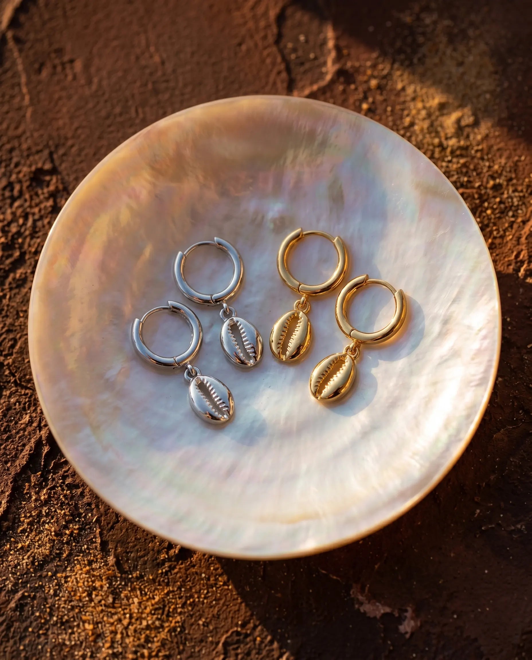 sand-cowrie-shell-earrings-displayed-on-mother-of-pearl-shell-highlighting-the-organic-design-and-sterling-silver-quality