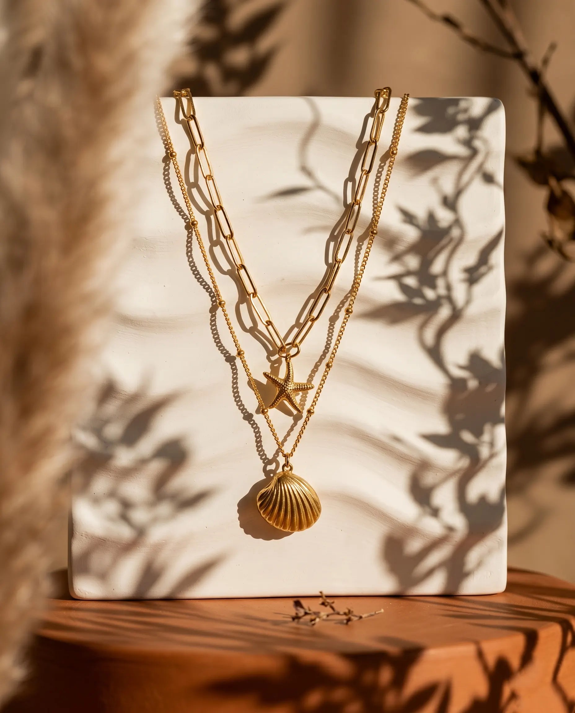 sunae-layered-necklace-displayed-on-textured-background-with-sea-inspired-charms-modern-coastal-jewelry-photography
