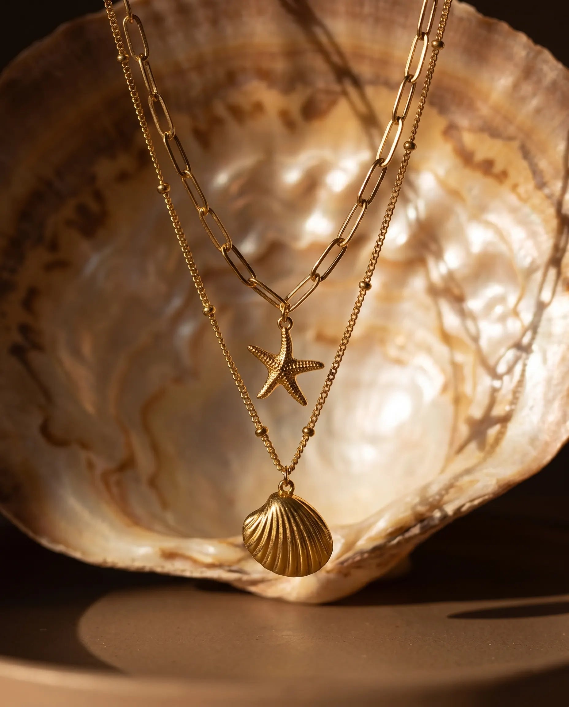 sunae-layered-necklace-displayed-on-textured-background-with-sea-inspired-charms-modern-coastal-jewelry-photography