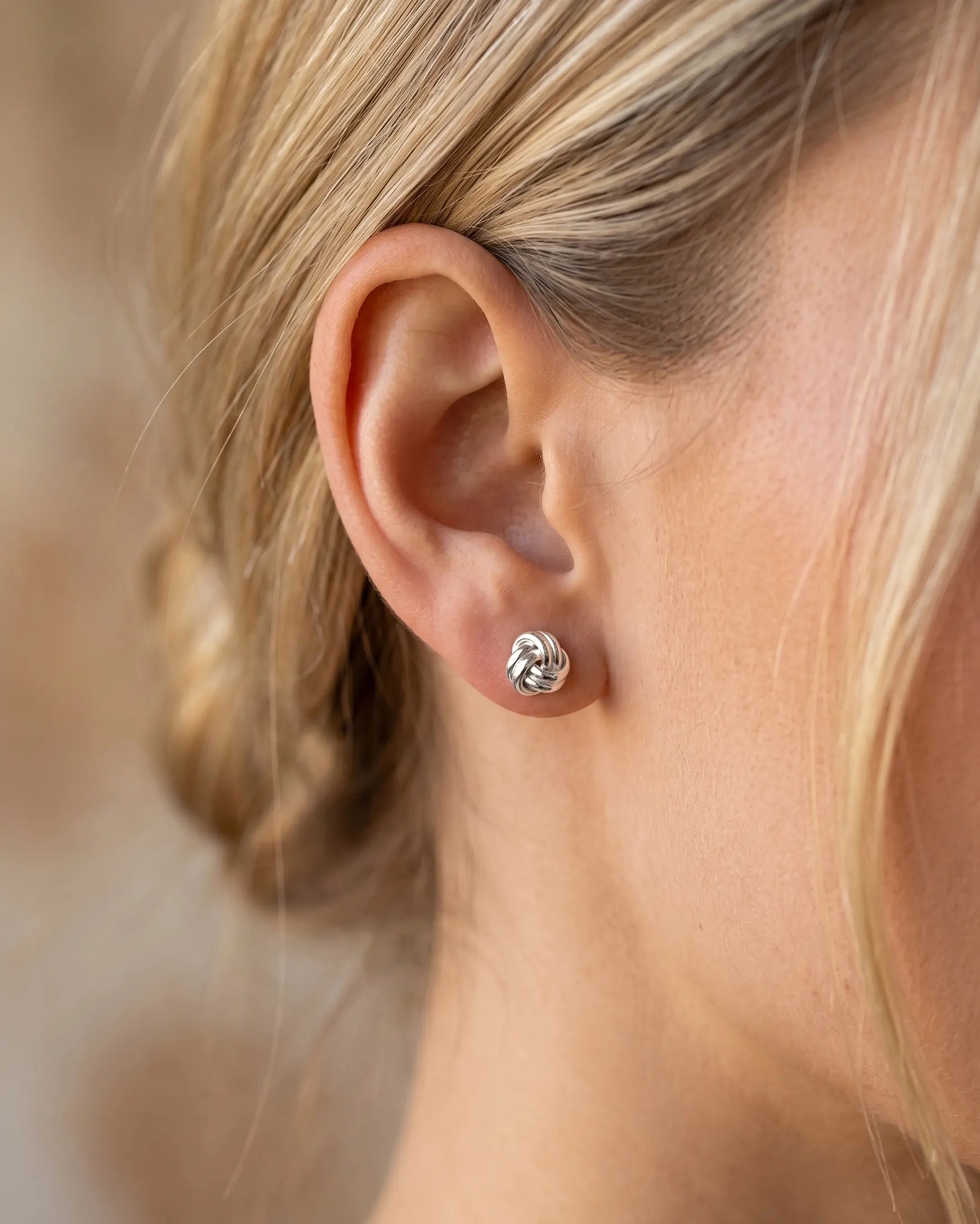 timeless-knot-design-earrings-gold-silver-mix, artistic-jewelry-photography-shadows, gift-ideas-for-women-silver-earrings, small-knot-studs-high-shine-finish, polished-925-silver-studs-premium, refined-jewelry-collection-germany
