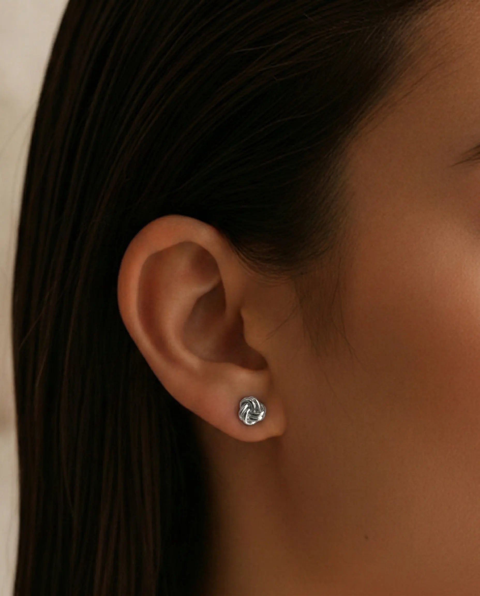 timeless-knot-design-earrings-gold-silver-mix, artistic-jewelry-photography-shadows, gift-ideas-for-women-silver-earrings, small-knot-studs-high-shine-finish, polished-925-silver-studs-premium, refined-jewelry-collection-germany