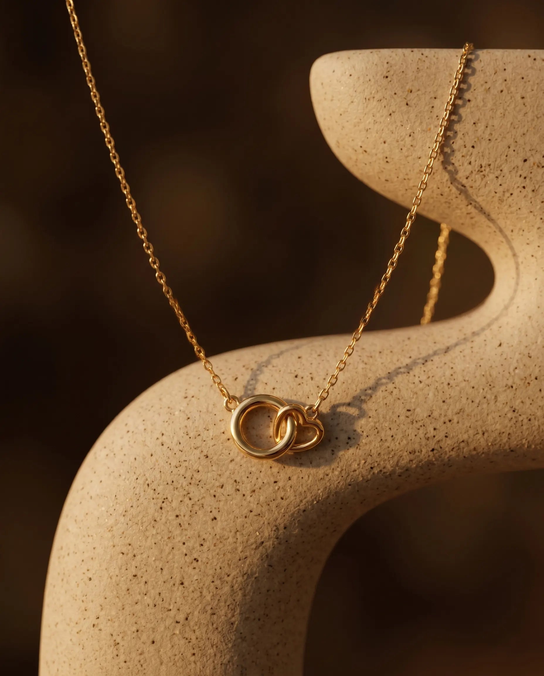 timeless-modern-aesthetic-interlocking-necklace-gold, 18k-gold-vermeil-finish-detail-valentina-pendant, gift-ideas-for-women-symbolic-jewelry, luxury-boutique-jewelry-netherlands, artistic-jewelry-flatlay-photography